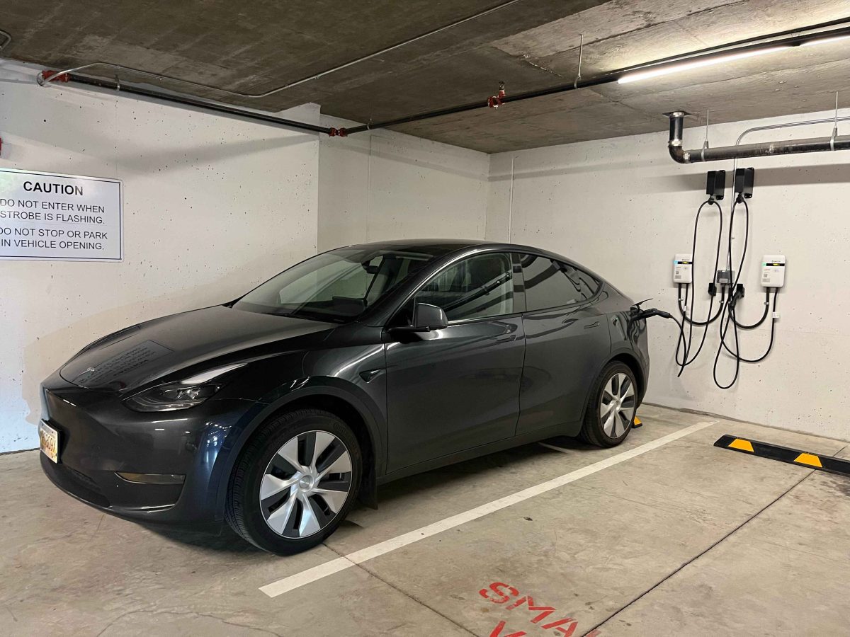 A dark grey Tesla is parked and charging at home EV charging station