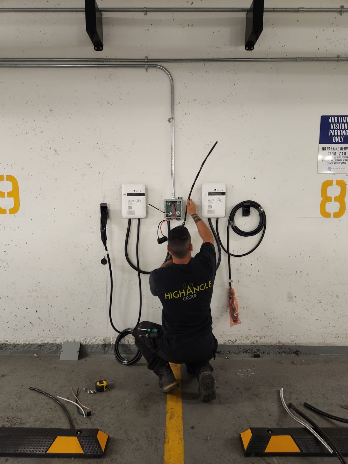 A technician installs electric vehicle (EV) charging stations in a parking garage.