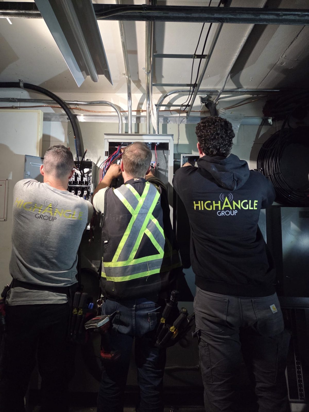 three electricians from High Angle Group working on electrical installations